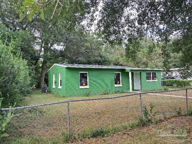 view of front facade with concrete block siding, fence, and central air condition unit