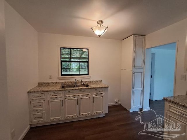 kitchen with sink, light stone counters, and dark hardwood / wood-style flooring