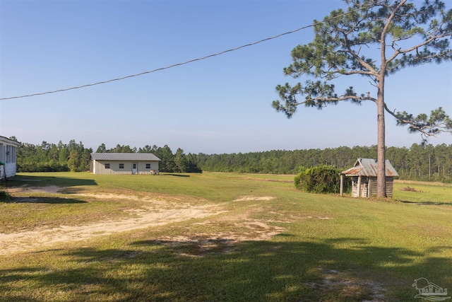 view of yard with driveway, a rural view, and a forest view
