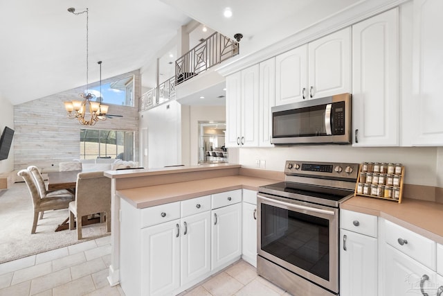 kitchen featuring a peninsula, appliances with stainless steel finishes, white cabinetry, and decorative light fixtures