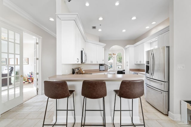 kitchen with appliances with stainless steel finishes, arched walkways, french doors, and white cabinetry