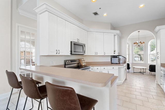 kitchen featuring a peninsula, white cabinetry, stainless steel appliances, and light countertops