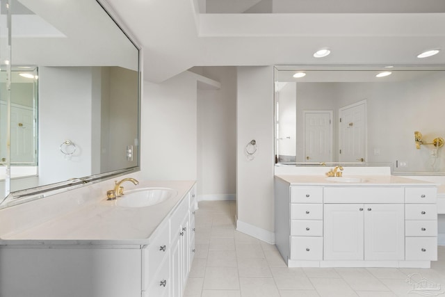 full bathroom with two vanities, a sink, tile patterned flooring, and baseboards