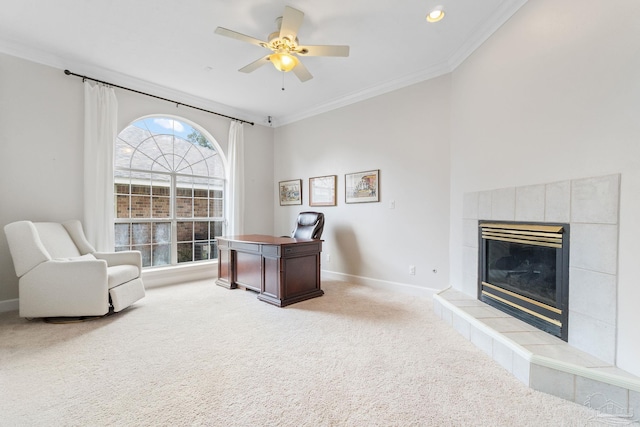 office space featuring crown molding, light carpet, ceiling fan, a tile fireplace, and baseboards