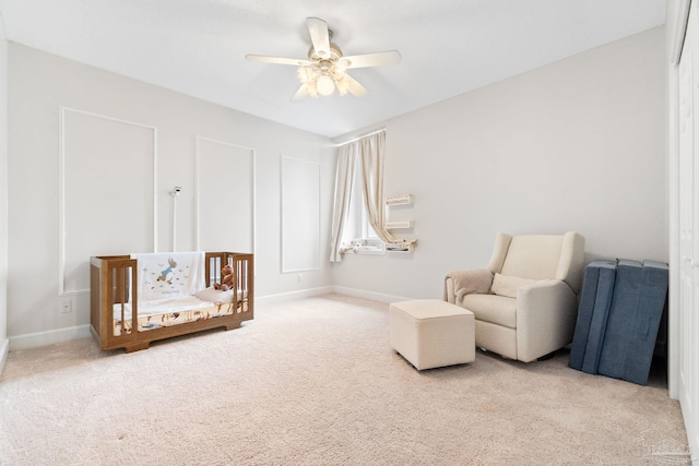 sitting room featuring light carpet, baseboards, and a ceiling fan