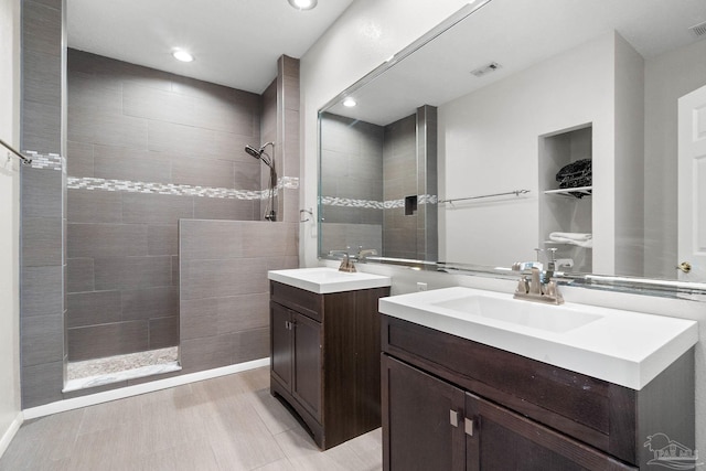 bathroom featuring a walk in shower, a sink, two vanities, and visible vents