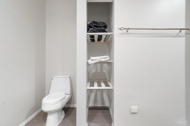 bathroom with tile patterned flooring, baseboards, and toilet