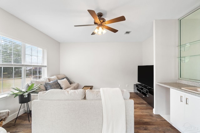 living area with visible vents, dark wood finished floors, baseboards, and ceiling fan