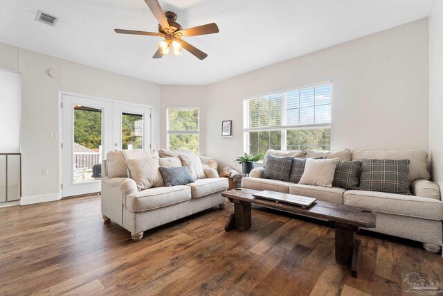 living area with a healthy amount of sunlight, visible vents, dark wood-type flooring, and french doors