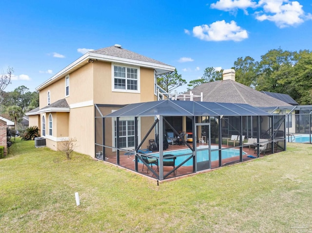 back of property featuring a yard, a chimney, stucco siding, glass enclosure, and an outdoor pool