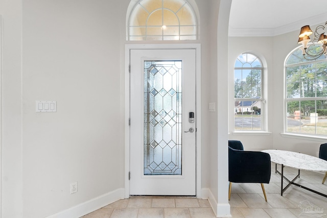 entryway featuring crown molding, baseboards, and an inviting chandelier