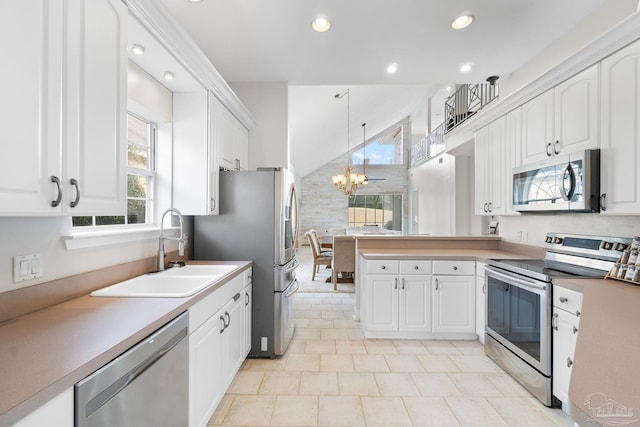 kitchen featuring stainless steel appliances, a peninsula, a sink, white cabinets, and decorative light fixtures