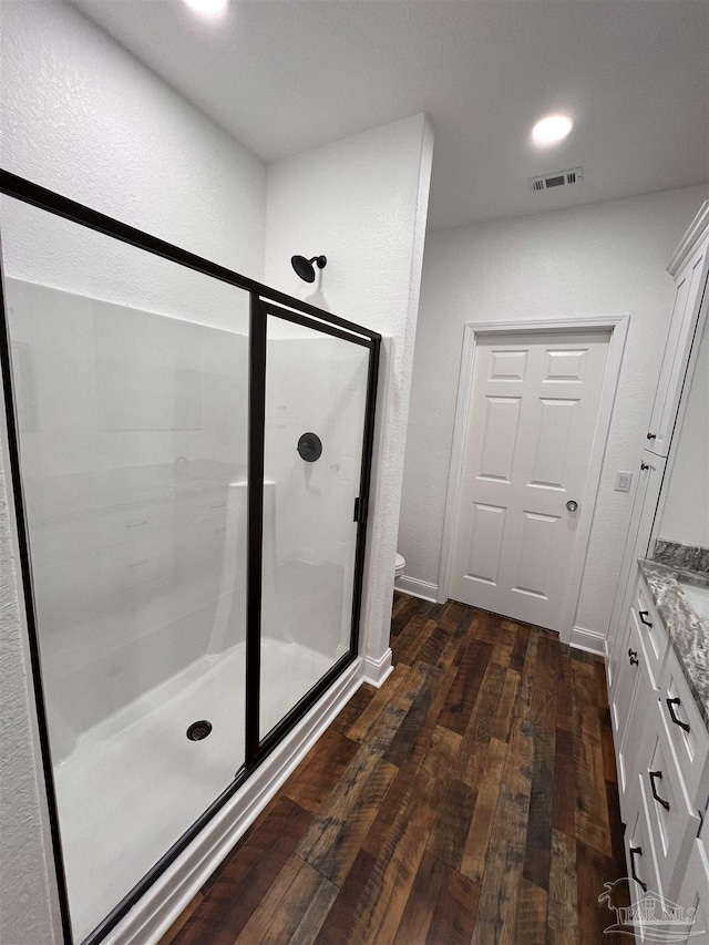 bathroom with vanity, hardwood / wood-style flooring, toilet, and walk in shower