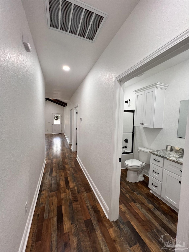 hallway featuring dark wood-type flooring and lofted ceiling