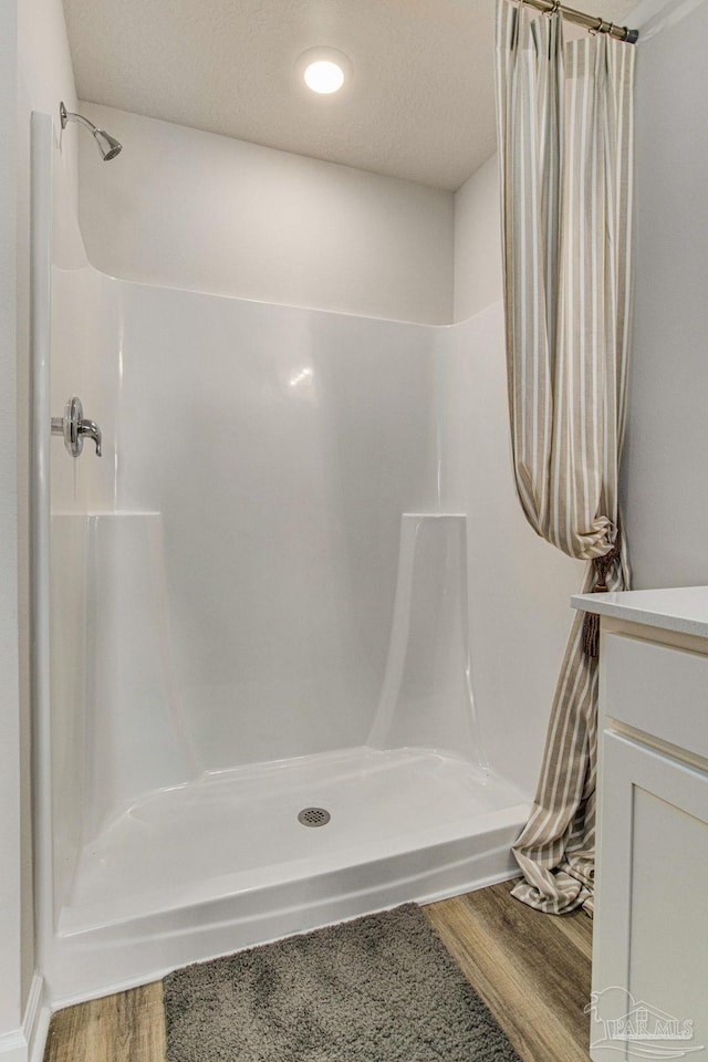 bathroom with a shower with shower curtain, a textured ceiling, hardwood / wood-style flooring, and vanity