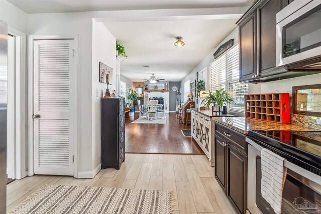 2543 Bayview Way, Pensacola, FL 32503 - kitchen featuring appliances with stainless steel finishes, a fireplace, a ceiling fan, dark brown cabinetry, and light wood finished floors