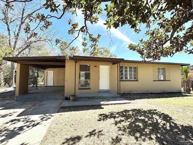 view of front of house with driveway, an attached carport, and stucco siding