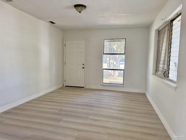 empty room featuring light wood finished floors, visible vents, and baseboards