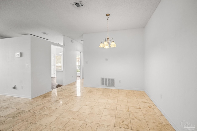 empty room featuring a textured ceiling and an inviting chandelier