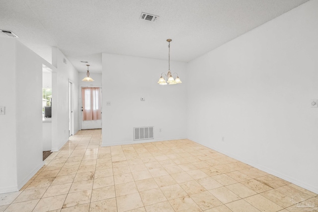 tiled spare room featuring a textured ceiling and an inviting chandelier