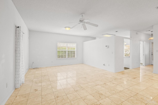 tiled empty room with ceiling fan and a textured ceiling