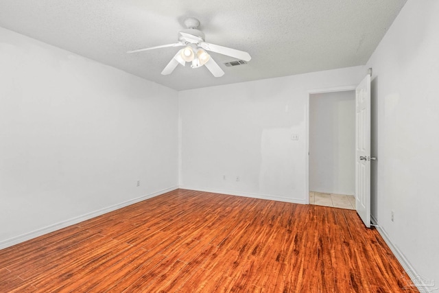 spare room featuring ceiling fan, light hardwood / wood-style floors, and a textured ceiling