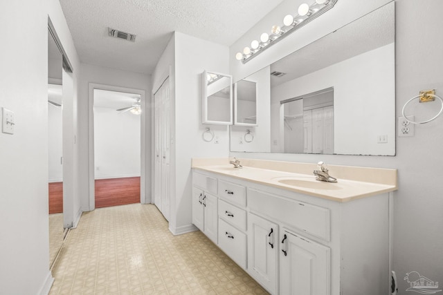 bathroom featuring ceiling fan, vanity, and a textured ceiling