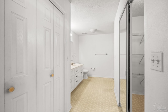 bathroom featuring vanity, a textured ceiling, and toilet