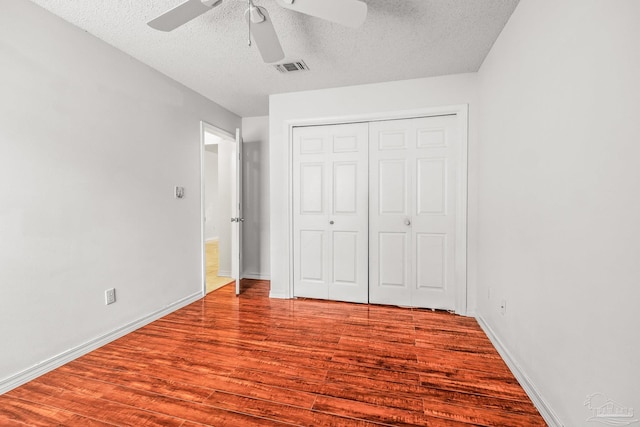 unfurnished bedroom featuring hardwood / wood-style floors, ceiling fan, a textured ceiling, and a closet