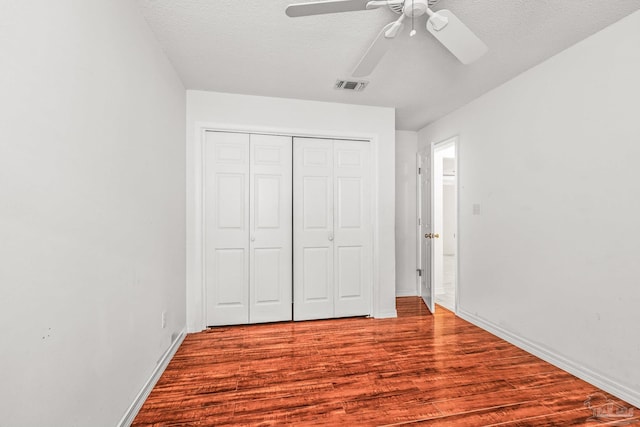 unfurnished bedroom with a closet, ceiling fan, hardwood / wood-style floors, and a textured ceiling