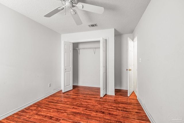 unfurnished bedroom with a closet, a textured ceiling, hardwood / wood-style flooring, and ceiling fan