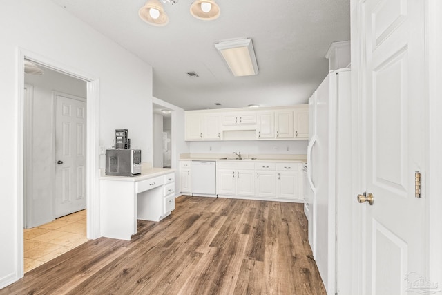 kitchen featuring wood-type flooring, white appliances, white cabinetry, and sink