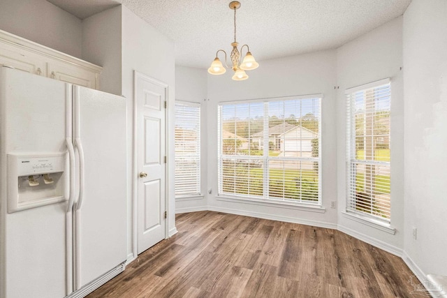 unfurnished dining area with a notable chandelier, wood-type flooring, and a textured ceiling