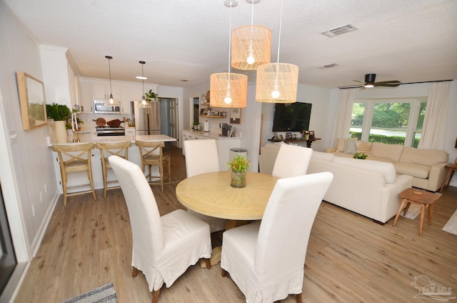 dining space featuring a textured ceiling, light hardwood / wood-style flooring, and ceiling fan