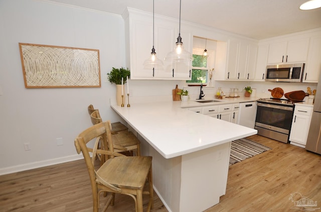 kitchen with white cabinetry, sink, kitchen peninsula, pendant lighting, and appliances with stainless steel finishes