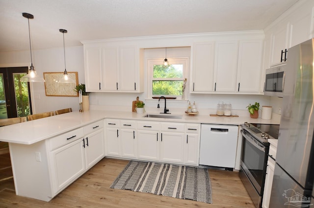 kitchen featuring kitchen peninsula, appliances with stainless steel finishes, sink, white cabinetry, and hanging light fixtures