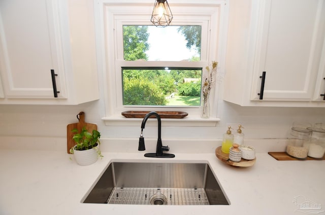 room details with white cabinets, pendant lighting, and sink