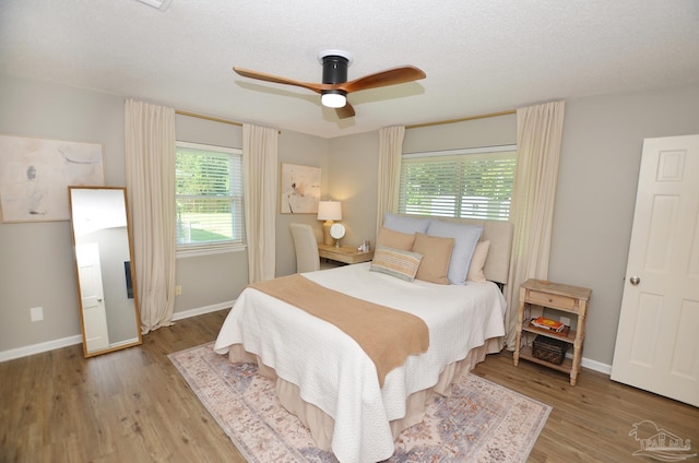 bedroom featuring ceiling fan, light hardwood / wood-style flooring, and a textured ceiling