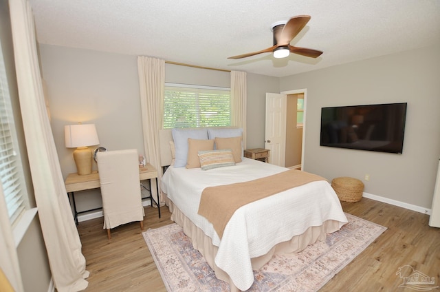 bedroom with ceiling fan, light hardwood / wood-style floors, and a textured ceiling