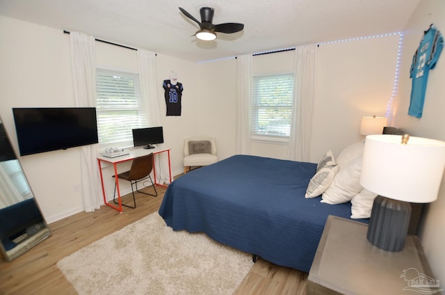 bedroom featuring ceiling fan, light wood-type flooring, and multiple windows