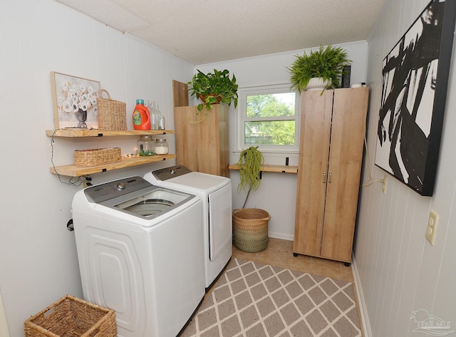 washroom with light tile patterned floors, a textured ceiling, wood walls, and washing machine and clothes dryer