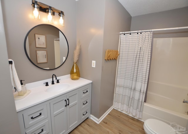 full bathroom with shower / bathtub combination with curtain, hardwood / wood-style floors, a textured ceiling, toilet, and vanity