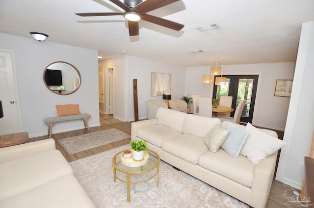 living room featuring a textured ceiling, light hardwood / wood-style floors, and ceiling fan