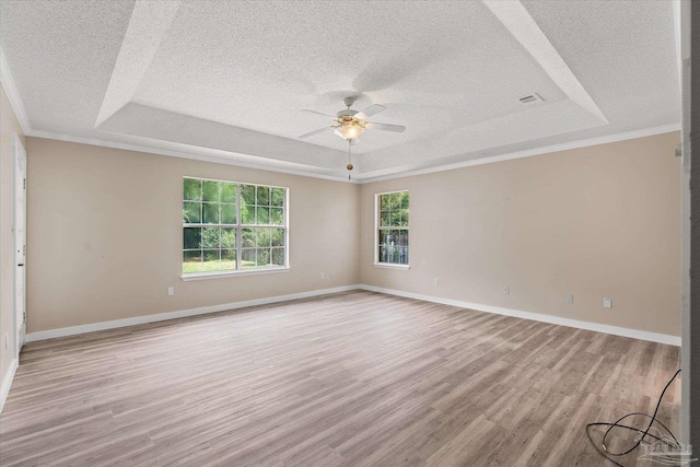 spare room with ceiling fan, ornamental molding, a textured ceiling, a tray ceiling, and light hardwood / wood-style floors