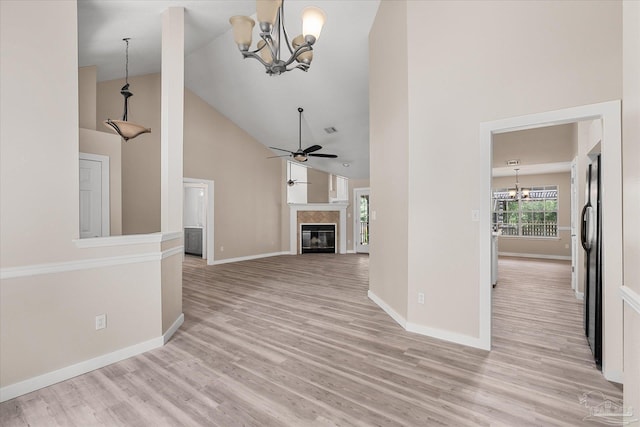 unfurnished living room with light hardwood / wood-style flooring, a high end fireplace, ceiling fan with notable chandelier, and high vaulted ceiling