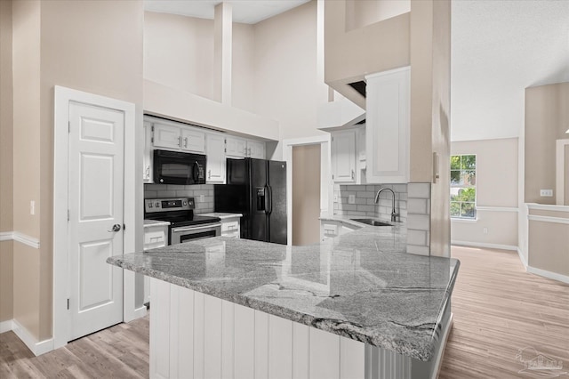 kitchen with backsplash, kitchen peninsula, sink, and black appliances