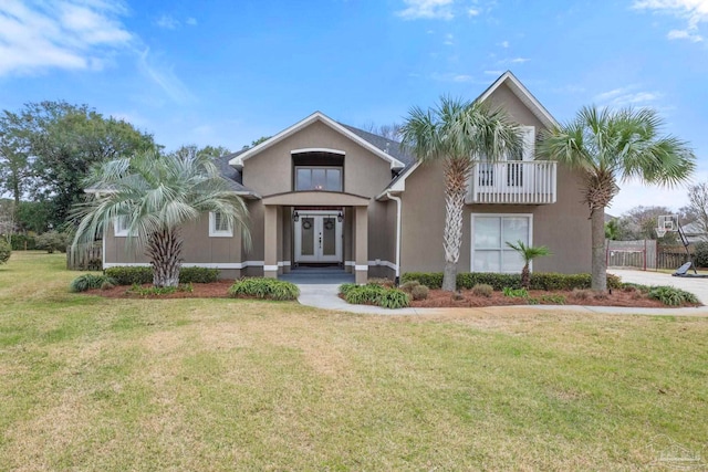 view of front facade featuring french doors, a balcony, a front lawn, and stucco siding