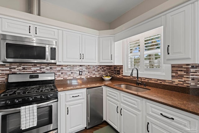 kitchen with stainless steel appliances, a sink, and white cabinets