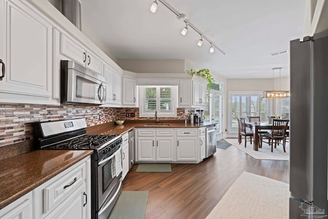 kitchen featuring stainless steel appliances, a sink, white cabinetry, backsplash, and dark wood finished floors