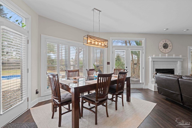 dining area featuring a fireplace, baseboards, and dark wood finished floors